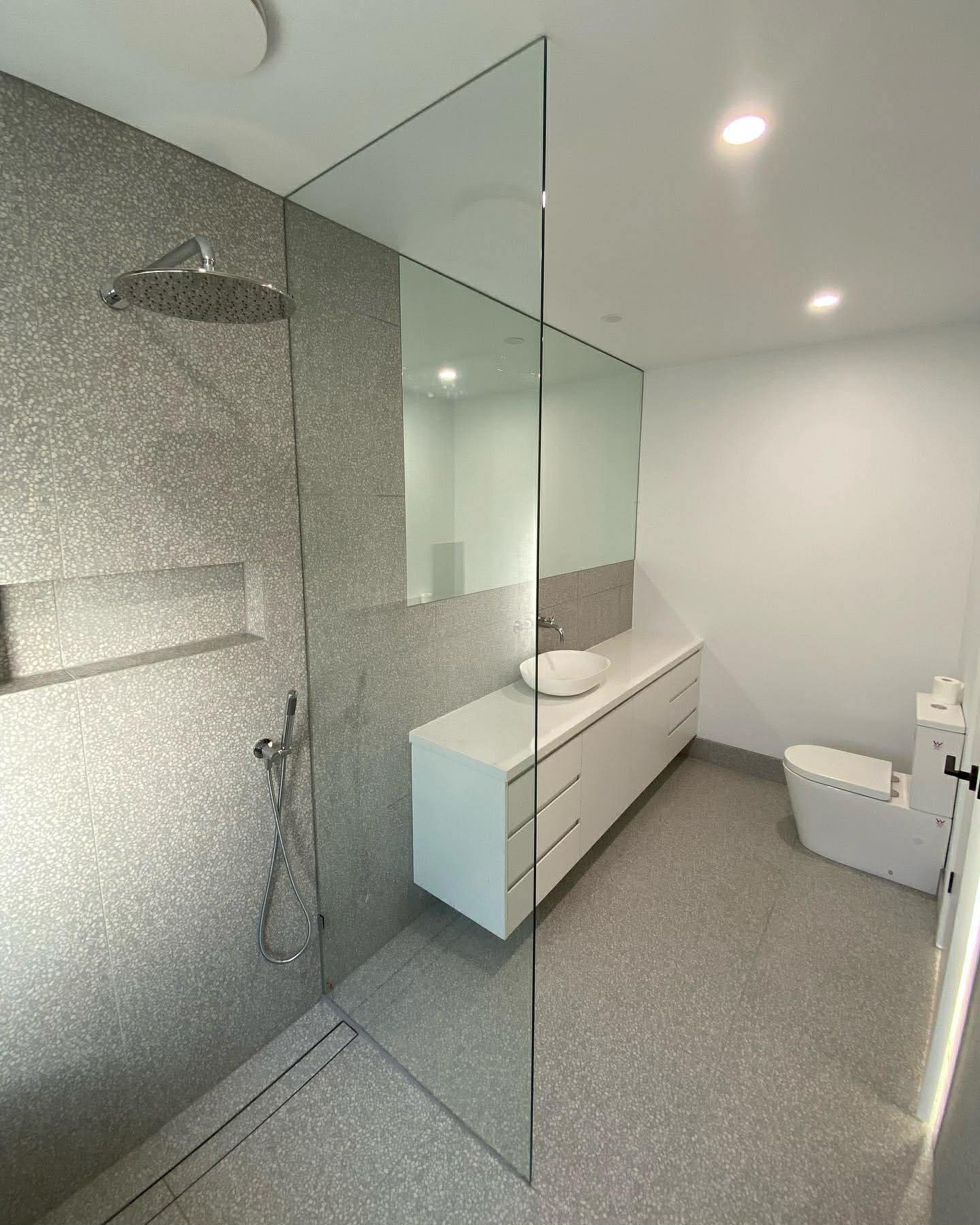 Frameless walk-in glass partition with terrazzo tiles