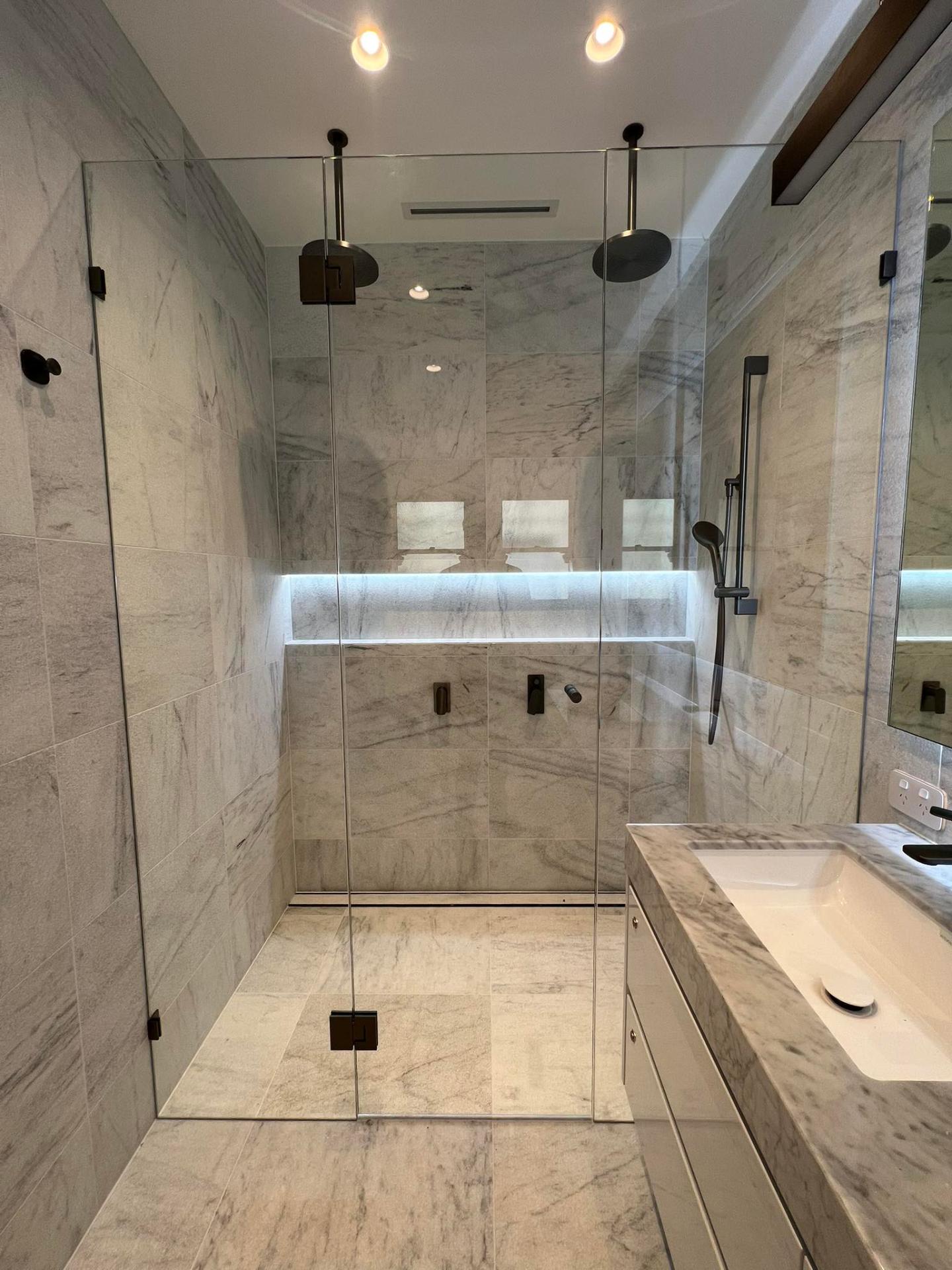 Frameless shower screen in a marble bathroom suite
